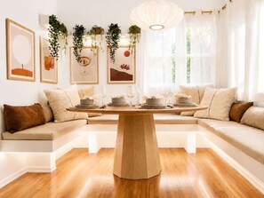 Ein moderner Essbereich mit Holztisch, gepolsterten Sitzmöglichkeiten und gerahmten Kunstwerken an den Wänden.