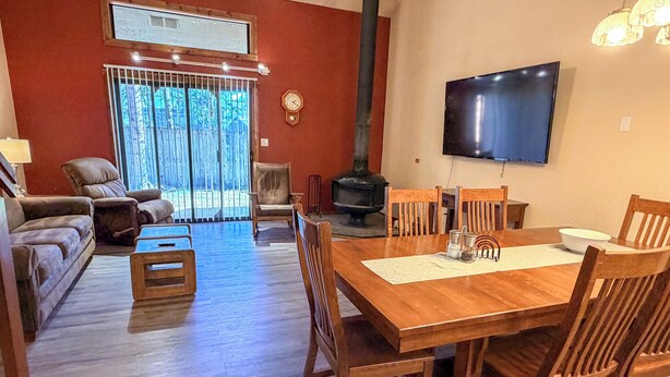 A living room with a fireplace, a TV mounted on the wall, and a dining area with wooden furniture.