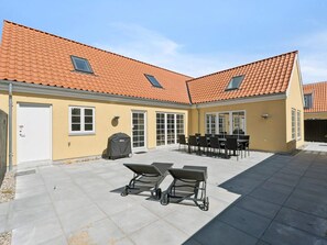 A building with a yellow exterior, red-tiled roof, and a patio area with outdoor furniture. - 4 Star Holiday Home in Skagen (Skagen)