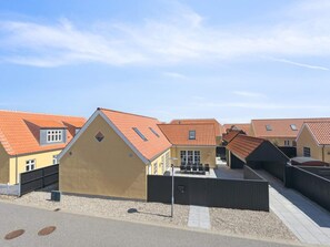 A row of yellow buildings with red-tiled roofs, a gated entrance, and a paved pathway. - 4 Star Holiday Home in Skagen (Skagen)