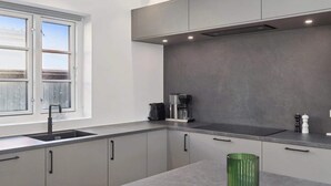 Una cocina moderna con armarios grises, un lavabo de acero inoxidable, una cafetera y un jarrón verde en la encimera.