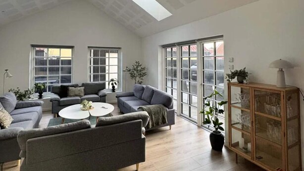 Un salón amplio con techo alto, ventanas grandes y una chimenea moderna.