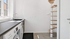 Un cuarto de lavado con una lavadora Siemens, un lavamanos y una escalera de madera.