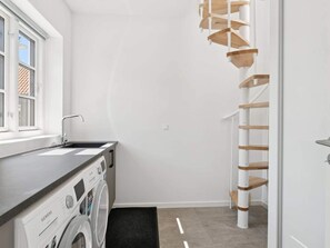 A laundry room with a Siemens washing machine, a sink, and a wooden ladder.