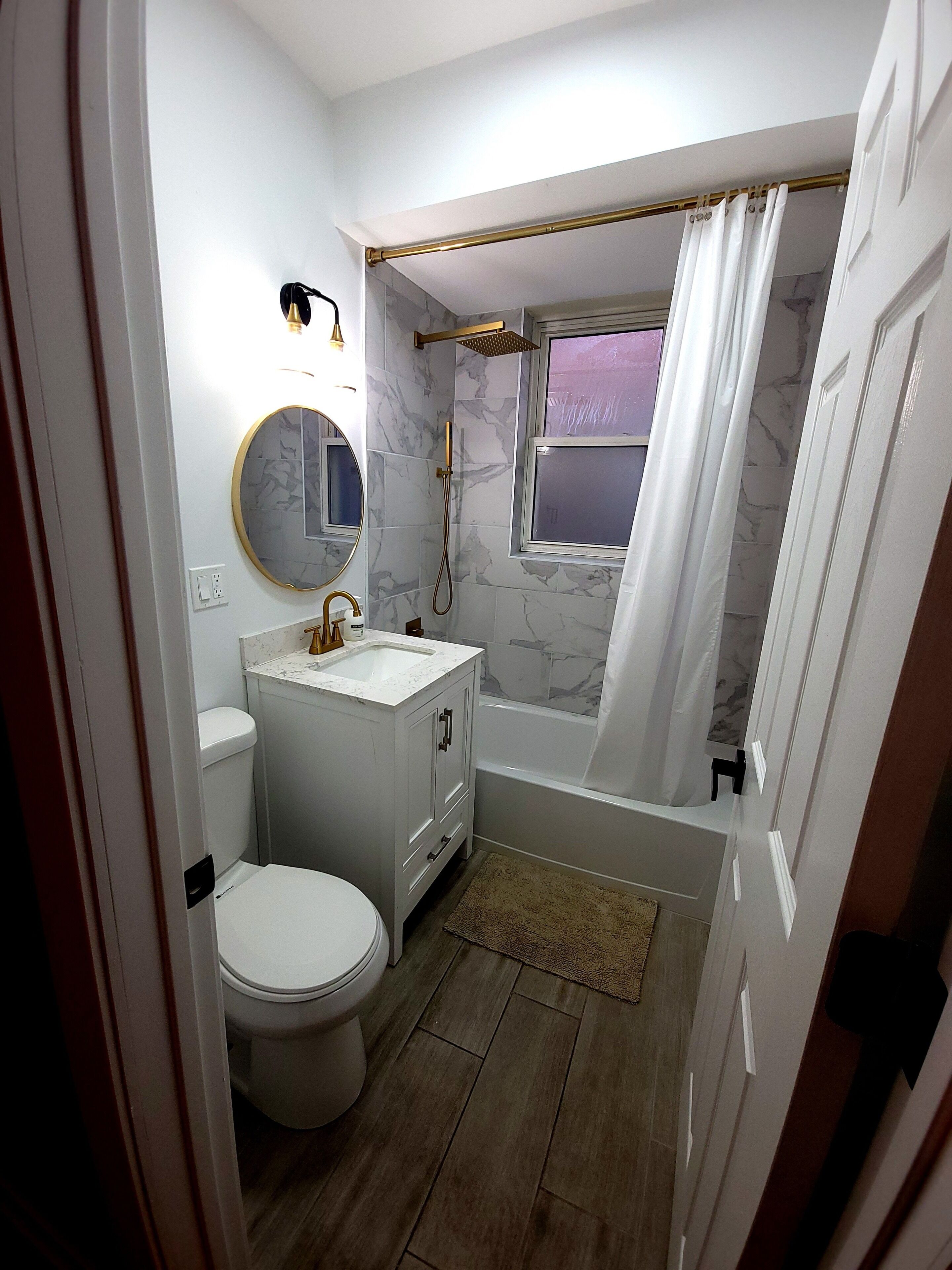 A bathroom with a toilet, sink, mirror, shower, and bathtub.