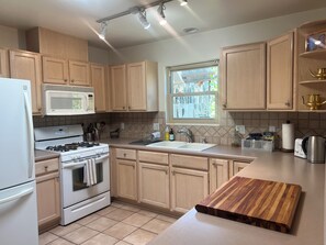 A modern kitchen with wooden cabinets, a white refrigerator, a microwave, a stove, and a sink. -  Sunny, Tranquil Two-Bedroom Home Near Santa Fe’s Best Attractions (Santa Fe)