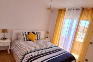A bedroom with a bed, two bedside tables, a lamp, and a window with curtains. - Beachfront 3BR Condo w/ Pool Views - Sleeps 10 (MC)