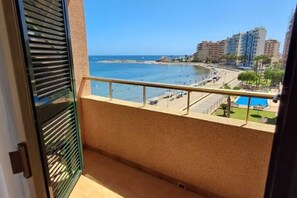 A balcony with a view of a beach, a pool, and buildings in the background. - Beachfront 3BR Condo w/ Pool Views - Sleeps 10 (MC)