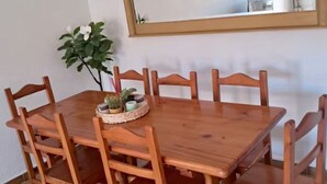Una mesa de madera para comer con seis sillas, una planta pequeña y un espejo en la pared.
