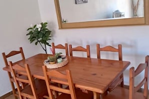 A wooden dining table with six chairs, a small plant, and a mirror on the wall. - Beachfront 3BR Condo w/ Pool Views - Sleeps 10 (MC)