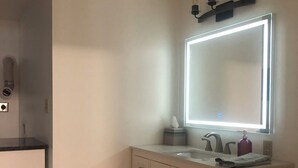 A bathroom with a vanity, a toilet, a mirror with lights, and a patterned floor. - Beautiful In-law suite in Palmyra PA. No Cleaning Fees. (Palmyra)