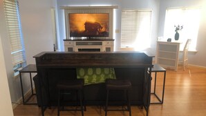 A bar area with a television, wooden bar counter, and stools. - Beautiful In-law suite in Palmyra PA. No Cleaning Fees. (Palmyra)