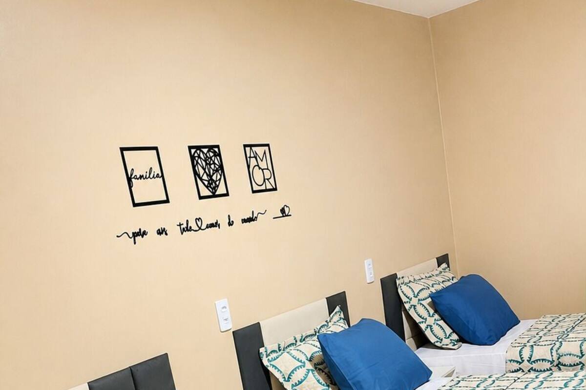 A hotel room with three beds, each with blue and white patterned bedding, and a wall with decorative wall art.