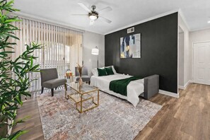 A modern living room with a sofa, a coffee table, a ceiling fan, and a painting on the wall. - Scottsdale Serenity | Pools, Patio, Pets OK (Scottsdale)