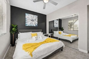 Een moderne slaapkamer met een groot bed, een plafondventilator, een spiegel en een kunstwerk aan de muur.