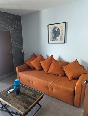 Ein Wohnzimmer mit einer Couch, einem Couchtisch, einem gerahmten Bild an der Wand und einer Tür.