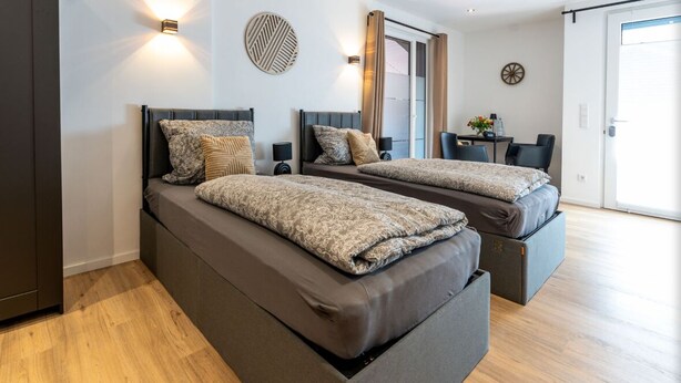 Een moderne slaapkamer met twee bedden, een klein tafeltje en uitzicht op buiten.