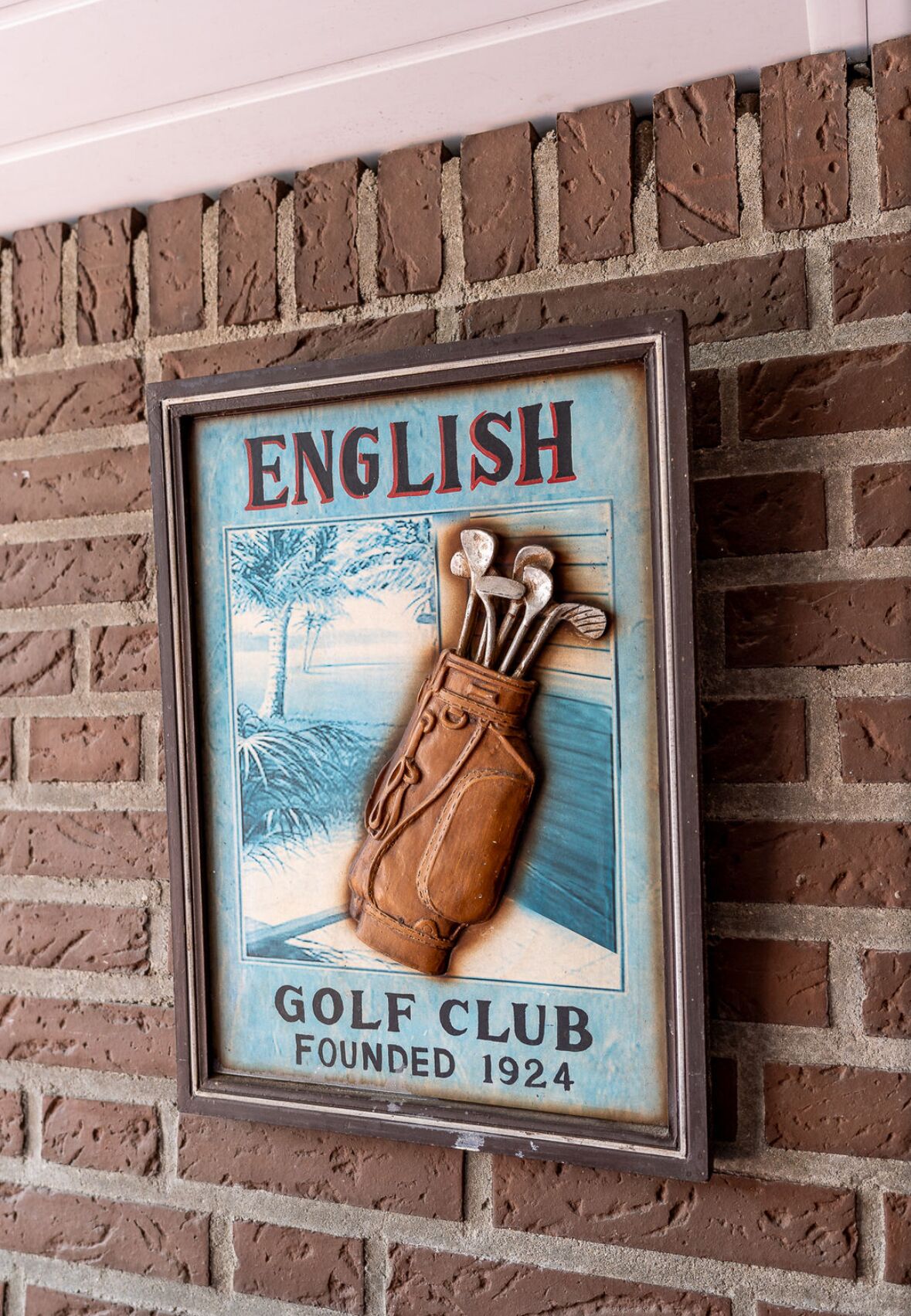 A framed sign with the text 'ENGLISH GOLF CLUB FOUNDED 1924' and an illustration of a golf bag.