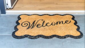 Welkomstmatje met het woord 'Welcome' op een deuropgang.