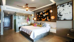 A modern bedroom with a bed, a ceiling fan, and abstract art on the walls. - Wake Up to Stunning Beach & Harbor Views (Puerto Vallarta)