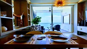 En matplats med utsikt över havet, en takfläkt och ett matbord dukat med tallrikar och bestick.