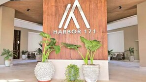 A wooden sign with 'HARBOR 171' and a logo, flanked by large potted plants. - Wake Up to Stunning Beach & Harbor Views (Puerto Vallarta)