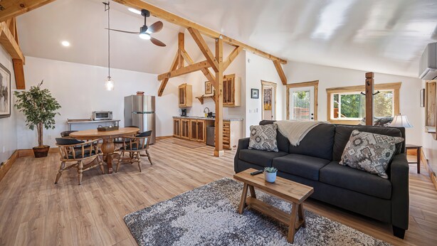 A spacious living area with a dining table, sofa, and kitchen in the background. - Barndo Hideaway at Hy Sun Ranch (Auburn)