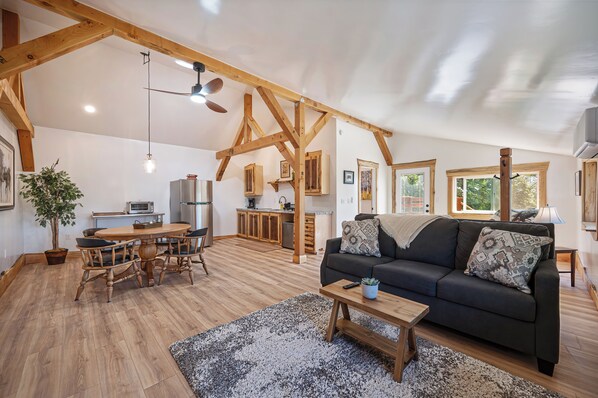 A spacious living area with a dining table, sofa, and kitchen in the background.