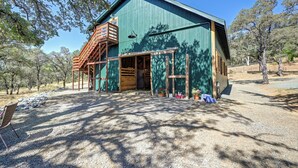 A rustic barn-style building with a wooden staircase, large windows, and a gravel driveway. - Barndo Hideaway at Hy Sun Ranch (Auburn)