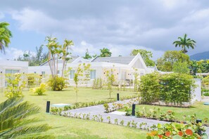 Un resort con varias edificaciones blancas, un césped cuidado y palmeras.