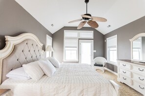 A bedroom with a large bed, a ceiling fan, a dresser, and a chair. - Oceanside, Pool, Walk to Beach! Pet Friendly! (Kitty Hawk)