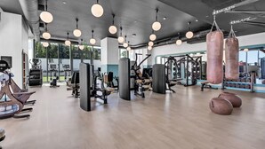 A gym with various exercise equipment, hanging lights, and large windows. - NoMad Residences Wynwood FIFA Fan Stay (Miami)