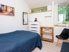 Ein Schlafzimmer mit Bett, Kommode, Stuhl, Fenster und einem Bild an der Wand.