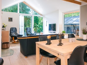Un interior moderno con comedor, asientos y ventanas amplias que ofrecen vistas a zonas verdes.