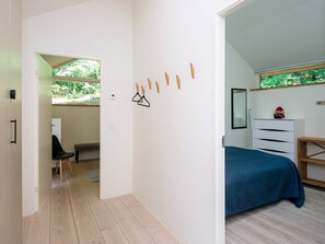 A bedroom with a bed, a dresser, and a mirror. There is a chair and a desk in the adjacent room. - 5 Star Holiday Home in Ans By (Ans)