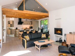 A modern living room with a black leather sofa, a wooden coffee table, and a fireplace. - 5 Star Holiday Home in Ans By (Ans)