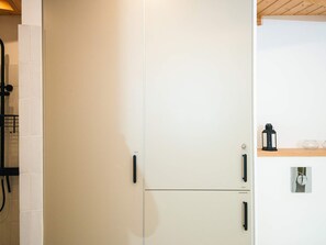 A kitchen with white cabinets, black handles, and a wooden ceiling. - 5 Star Holiday Home in Ans By (Ans)
