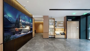 Un vestíbulo de hotel con un mural grande en la pared, un mostrador de recepción y una zona de estar.