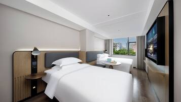 Una camera d'hotel moderna con un letto grande, un letto più piccolo, una scrivania e una televisione.