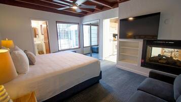 A bedroom with a bed, a TV, a fireplace, and a view of the outside.