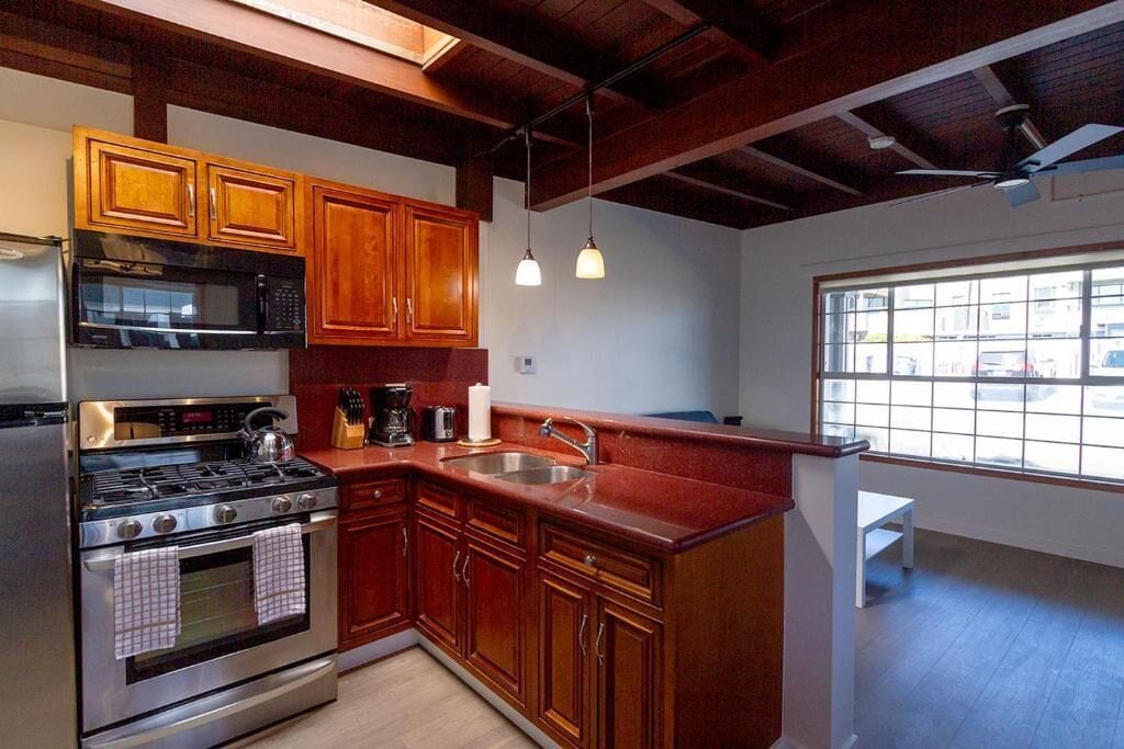 A kitchen with wooden cabinets, stainless steel appliances, and a window with a view.