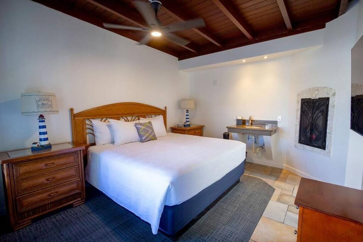 A bedroom with a wooden bed, a nightstand, a dresser, a vanity with a mirror, and a ceiling fan.