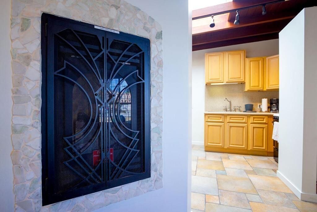 A stone wall with a decorative window, a kitchen with yellow cabinets, and a tiled floor.