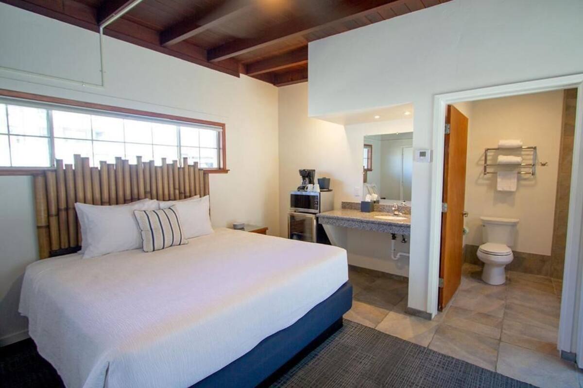 A hotel room with a bed, a bathroom, and a view of the outside.