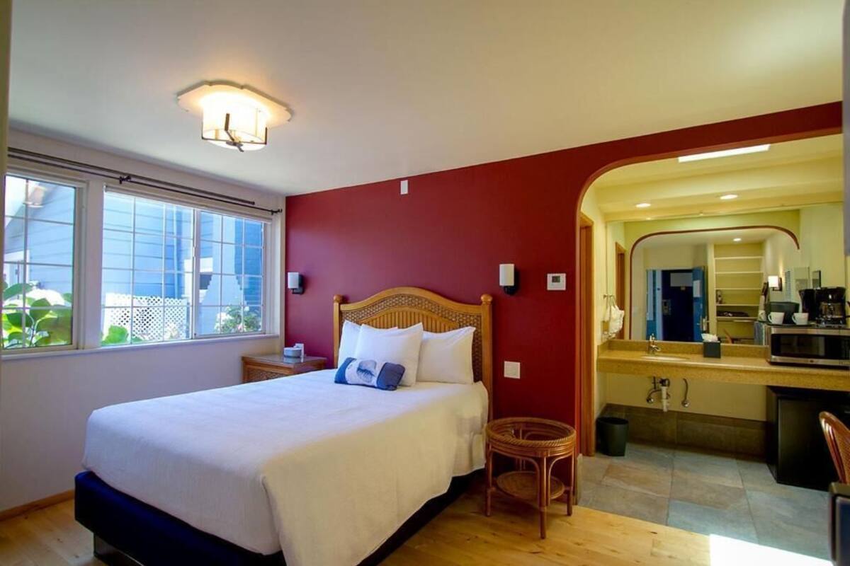 A bedroom with a bed, bedside table, and a view of the bathroom.