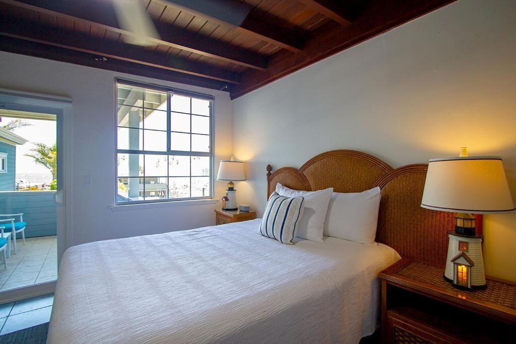 Un dormitorio con una cama grande, una ventana, una mesita de noche con lámpara y vistas al exterior.
