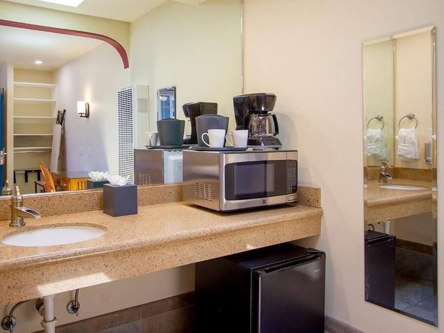 Ein Hotelbad mit Waschbecken, einer Kaffeemaschine, einem Spiegel und einem Mülleimer.