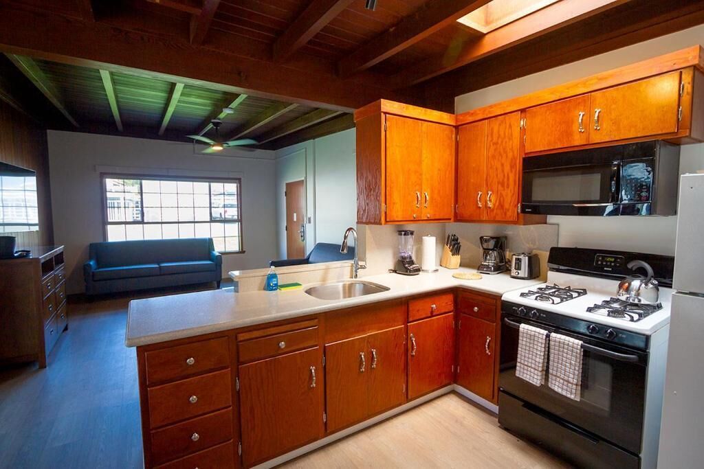 A kitchen with wooden cabinets, a gas stove, a microwave, and a sink.