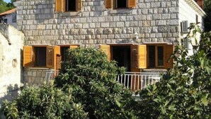 A stone building with wooden shutters, a balcony, and a white railing. - Old Town Bay Cavtat with Sea View (Cavtat)