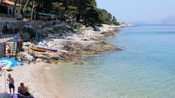 A beach with clear water, rocky shore, and umbrellas. - Old Town Bay Cavtat with Sea View (Cavtat)
